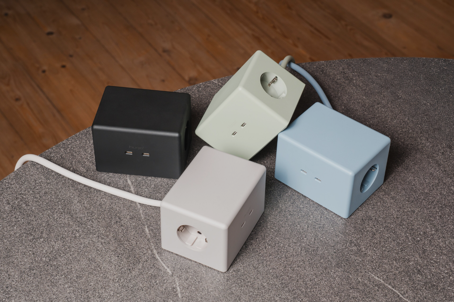 Vier hugo! ONE Steckdosenwürfel in deep black, cream white, ice blue und mint green.