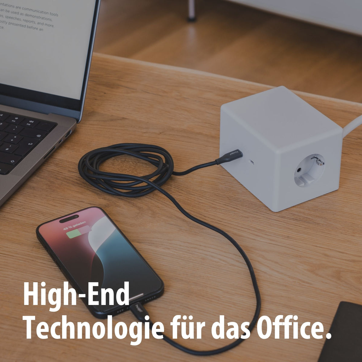 hugo! ONE lädt ein Smartphone am Schreibtisch.