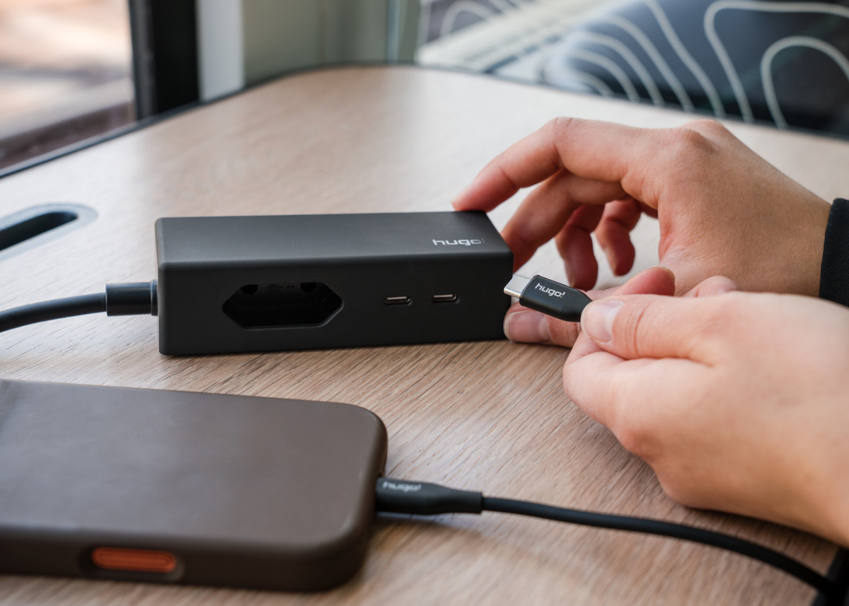 hugo! TRAVEL in deep black beim Einstecken eines USB C-Kabels.